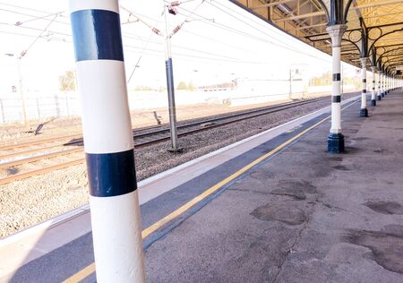 A view along a British train station platform during a sunny day. Multiple posts hold up the long platform shelter.の写真素材