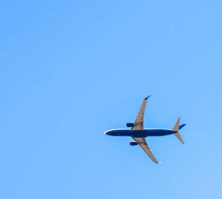 A large passenger aircraft seen from the ground up, high above ground level. Carrying passengers of...