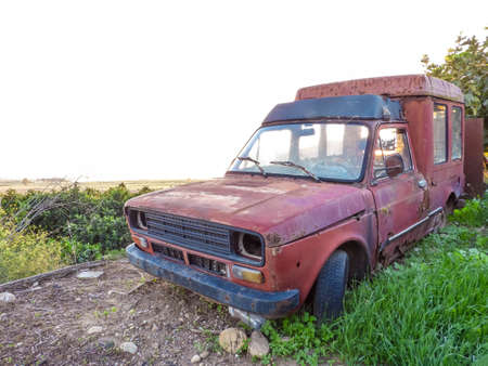 A very old and abandoned car in the middle of the crops in Sicily, Italy. The car being taken over...