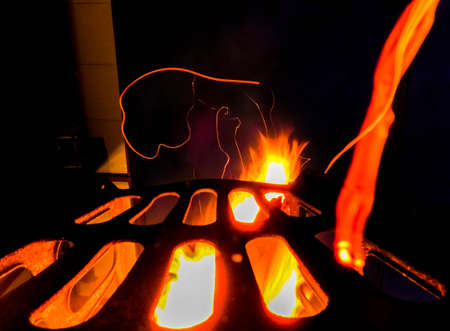 A fire which is in full flame to heat those around it, in a garden or remote location to keep people warm. The flames red and orange blast from the sides of the container.の写真素材