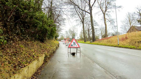 Roadworks being carried out on a steep incline of road. Signs and control measures in place to keep control of the traffic going up and down the road.の写真素材