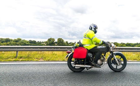 A vintage motorbike traveling alone one of the main United Kingdom motorways, seen from the side on...
