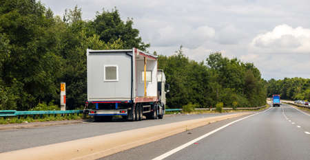 A large HGV vehicle traveling carrying a portacabin to be delivered or has just been collected from factory or customer parked up in a lay by on the side of a motorway or dual carriageway in United Kingdom.の写真素材
