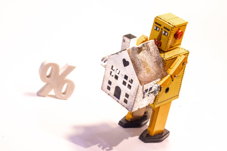 A robot person stand side by side with an interest rates / percentage sign close by, against a white background.の写真素材