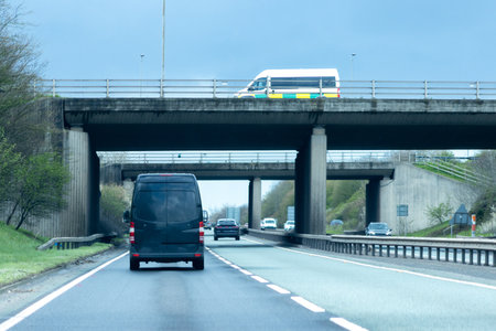 A 'white' van traveling along a main road in the United Kingdom, the roads wet and dirty.の写真素材