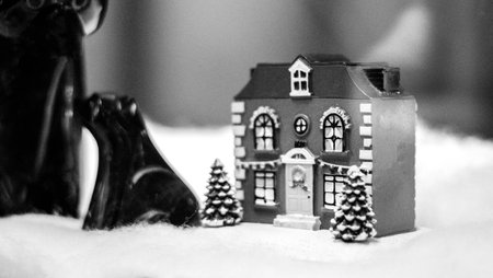 A small Christmassy house ornament sitting on fake snow.の写真素材