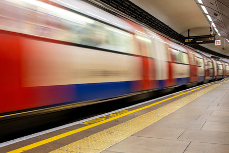 A view from a train station platform as a passenger train flies past at high speed.の写真素材