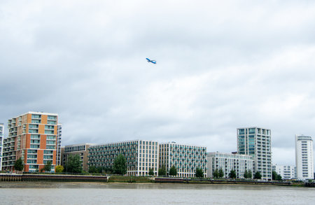 A large commercial aircraft taking off, flying over the Royal Victoria Dock.の写真素材