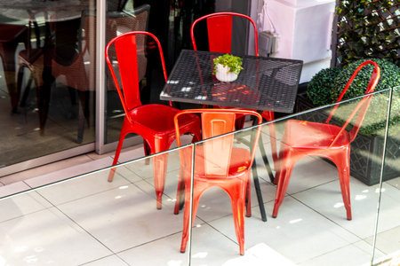 Red seats around a table that has been put outside so customers can sit out in the sun or fresh air.の写真素材