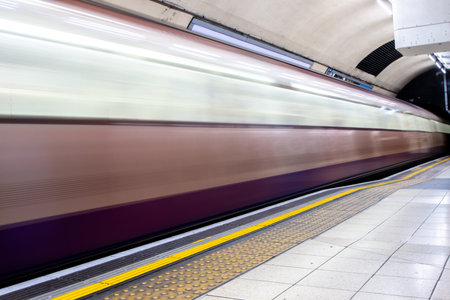 A view from a train station platform as a passenger train flies past at high speed.の写真素材
