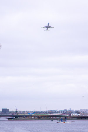 A large commercial aircraft taking off from London City Airport, in the United Kingdom, flying over the Royal Victoria Dock.の写真素材