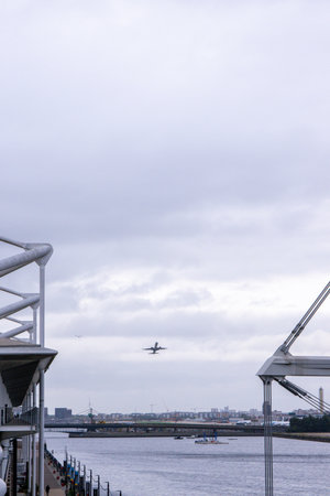 A large commercial aircraft taking off from London City Airport, in the United Kingdom, flying over the Royal Victoria Dock.の写真素材