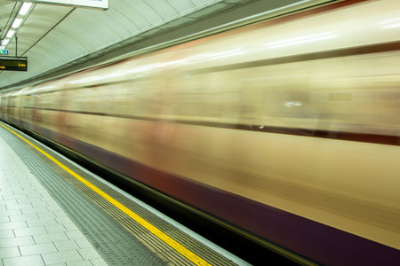 A view from a train station platform as a passenger train flies past at high speed.の写真素材