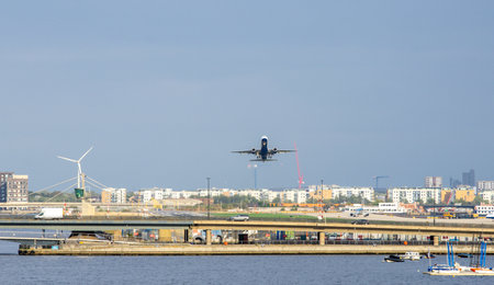 A large commercial aircraft taking off, flying over the Royal Victoria Dock.の写真素材