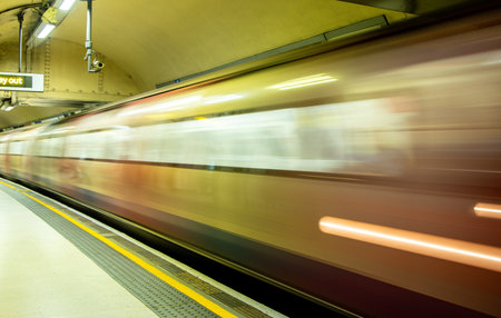 A view from a train station platform as a passenger train flies past at high speed.の写真素材