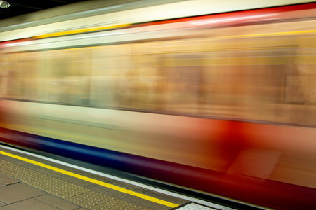 A view from a train station platform as a passenger train flies past at high speed.の写真素材