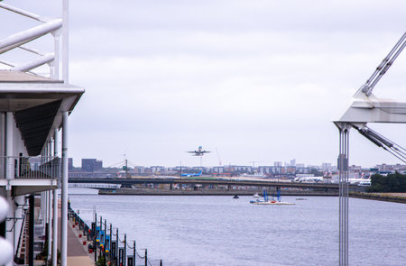 A large commercial aircraft taking off from London City Airport, in the United Kingdom, flying over the Royal Victoria Dock.の写真素材