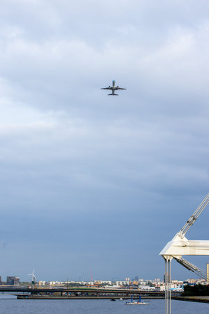 A large commercial aircraft taking off from London City Airport, in the United Kingdom, flying over the Royal Victoria Dock.の写真素材
