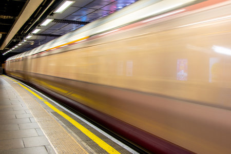 A view from a train station platform as a passenger train flies past at high speed.の写真素材