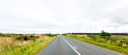 A dry day within the countryside as a vehicle drives along one of the thousands of country roads, within the United Kingdom.の写真素材