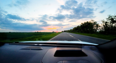 A vehicle travelling down a road, in the United Kingdom, in the evening as the sun disappears. The roads are quiet.の写真素材