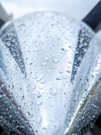 A very shiny, new, chrome spinner on the front of an aircraft's engine. Covered in rain drops.の写真素材