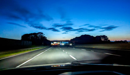A vehicle travelling down a road, in the United Kingdom, in the evening as the sun disappears. The roads are quiet.の写真素材