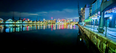 The Royal Victoria Docks surrounded by homes, cranes, businesses, hotels and activities. Seen here at night.の写真素材