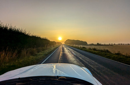 Awe inspiring colours as the sun goes down behind a lovely landscape, seen from a country road, within the United Kingdom.の写真素材