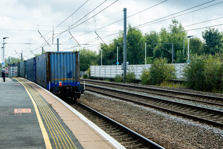 A very powerful freight train pulling it's loaded carriages past a station platform.の写真素材