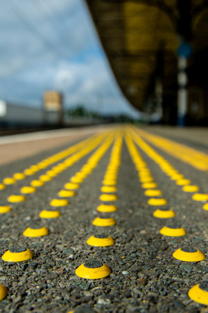 Along a train station platform can be found Tactile Ground Surface Indicators (TGSIs) which are indicators to blind people of the platform edge.の写真素材