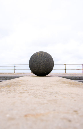A large concrete ball on the seafront wall.の写真素材