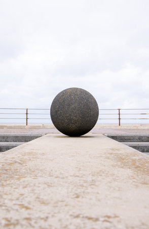 A large concrete ball on the seafront wall.の写真素材