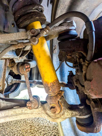 The underbody of a vehicle that is a little rusty, with a close up view of the suspension that enables the car to have a smoother ride.の写真素材