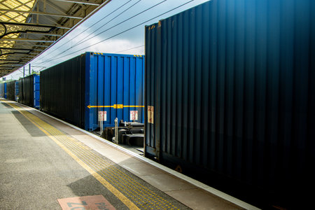 A very powerful freight train pulling it's loaded carriages past a station platform.の写真素材