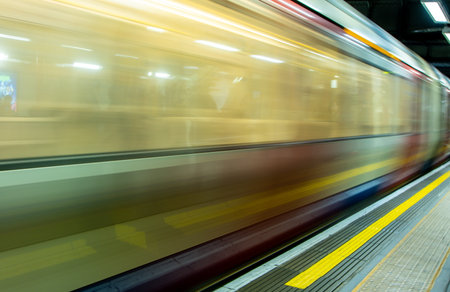 A view from a train station platform as a passenger train flies past at high speed.の写真素材