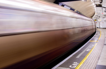 A view from a train station platform as a passenger train flies past at high speed.の写真素材