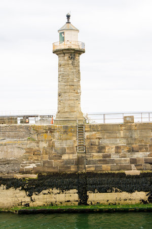 A small harbour lighthouse on the end of a pier, at Whitby in the United Kingdom. Used to warn ships of approaching land.の写真素材