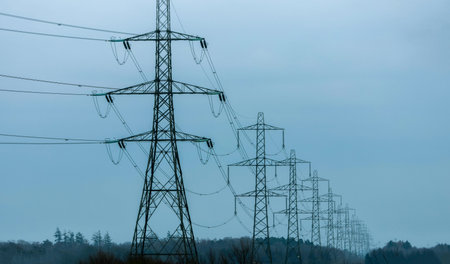Electricity pylons tower above and stretch across the landscape of the United Kingdom.の写真素材