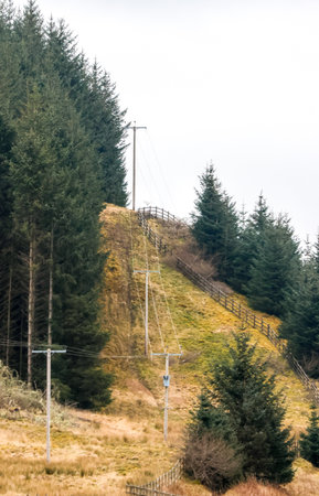 Electricity pylons tower above and stretch across the landscape of the United Kingdom.の写真素材