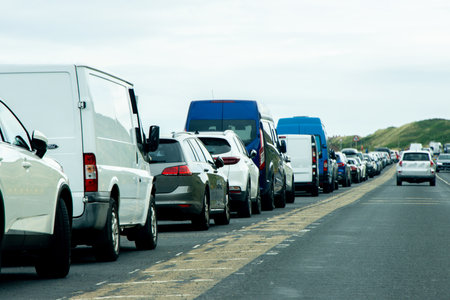 A busy single line of parked cars where people have stopped off to get to the beach.の写真素材