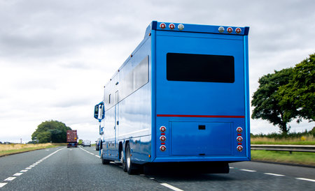 A large blue horse box carrier transporting horses down a dual carriageway to it's destination.