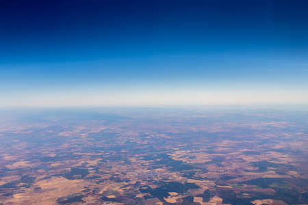 A passenger view from high above the earth's surface as an aircraft flies across the landscape.