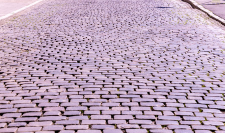 A very old style road made out of cobbles, strong but bumpy for vehicles to drive and people to walk across.の写真素材