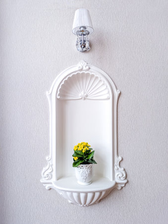 A stunning piece of architecture mounted on the wall, displaying a small flower in a plant pot bringing character and beauty to a building interior.の写真素材