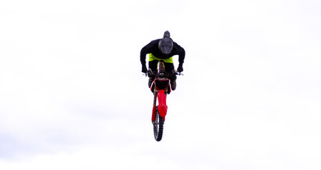 A motocross bike carrying out various stunts at an event with petrol head spectators watching on.