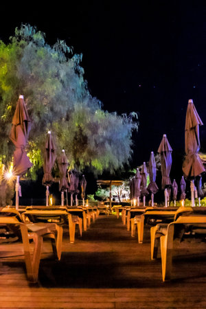 Sunloungers at the side of a swimming pool where people relax and enjoy sun by day and stars by night.の写真素材