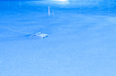 A small robot at the bottom of a resort swimming pool works through the night to clean the dirt etc for the next day's swimmers.の写真素材