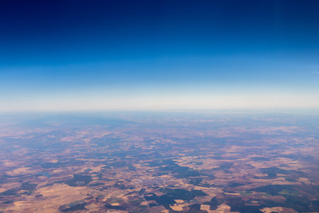 A passenger view from high above the earth's surface as an aircraft flies across the landscape.