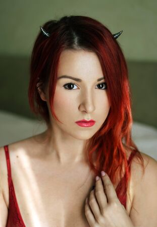 The sexy young woman with small devil's horns portraitの写真素材